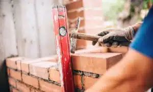 builder working with a spirit level and hammer on brick mortar repair