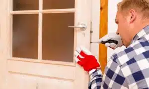 handyman uses a screwdriver to fix a door sticking