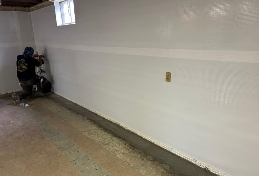 LUX technician installing vapor barrier in basement wall for interior waterproofing in Alexandria, VA.