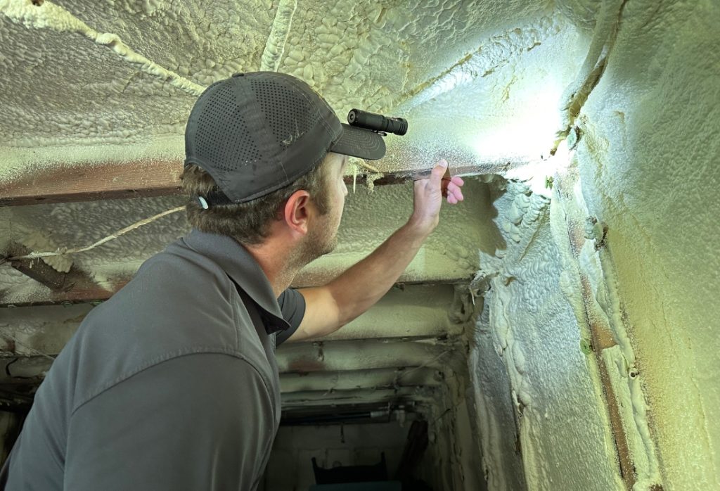Virginia contractor inspecting crawl space size and condition, key factors in encapsulation cost in Winchester, VA, homes.