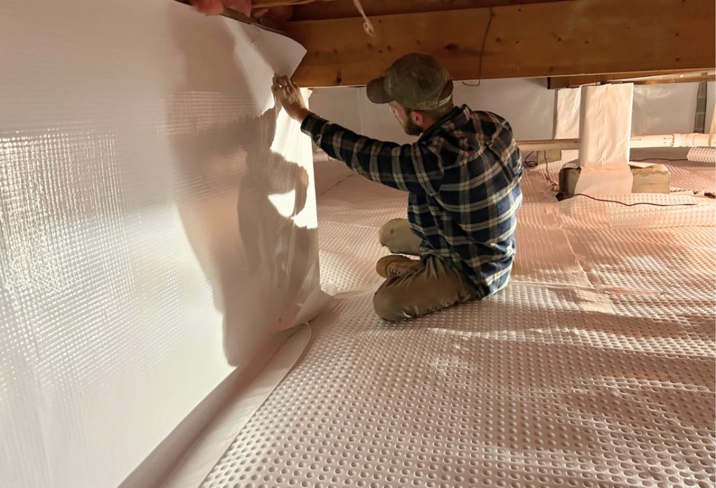 Professional crawl space contractor installing vapor barrier, showing why expert encapsulation in Martinsburg, WV, is safer than DIY.