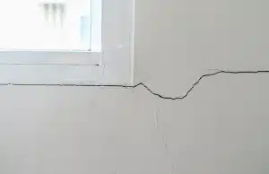 Cracks in drywall near a window, serving as a sign of sticking doors and windows in Manassas, VA.