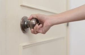 A man pulling a difficulty-opening door, a sign of sticking doors and windows in Brambleton, VA.