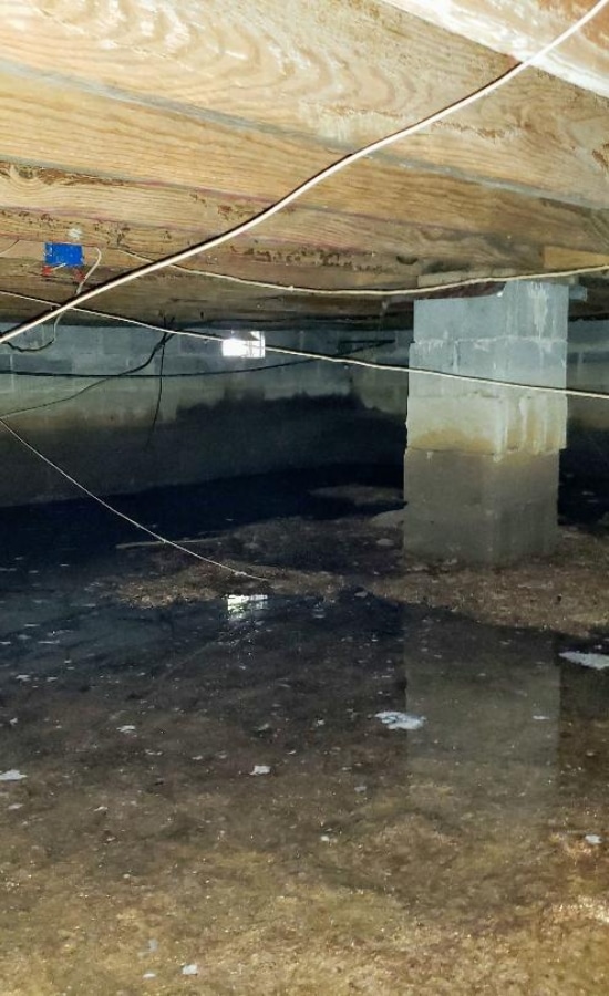A dirty crawlspace with standing water that needs solutions to eliminate the crawl space's musty odor in Northern Virginia.