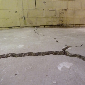A deep crack in a basement floor in Charles Town, WV, with the cause attributed to frost heave.