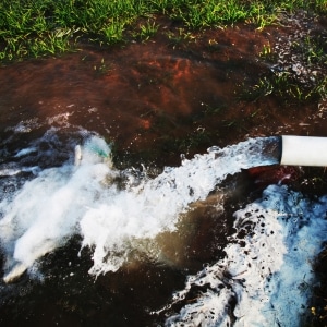 A drainage pipe with flowing water into the ground shows groundwater seepage causes crawl space condensation in Reston, VA.