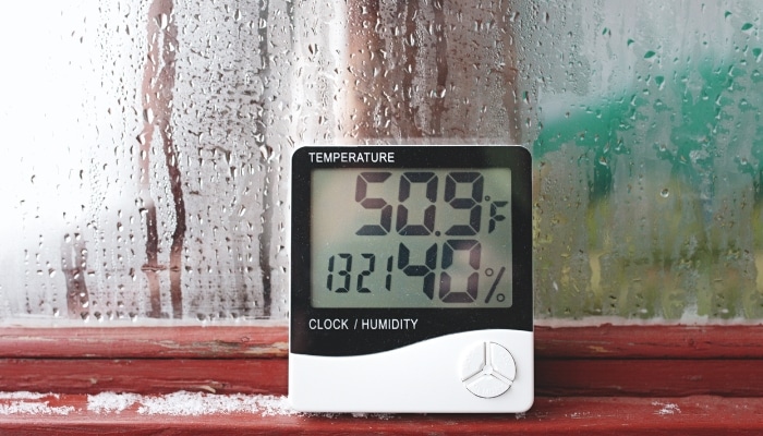 A window condensation and hygrometer showing high humidity levels in Northern Virginia, a symptom of underlying crawl space problems.