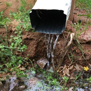 A drainage pipe with flowing and stagnant water, showing poor drainage as the cause of crawl space insulation in Reston, VA.