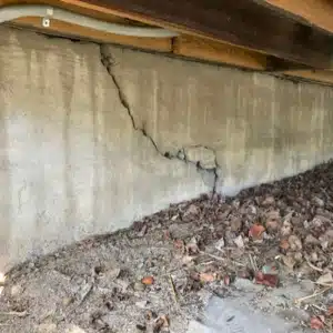 A crawl space wall with visible horizontal cracks showing poorly constructed crawl space can cause floor sagging in Linden, VA.