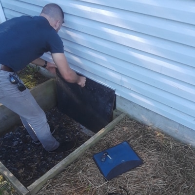 A man doing proper closure of vent and door in Linden, VA, a solution to manage air leakages causing crawl space condensation.