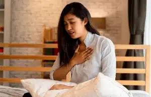 A girl holding her chest, feeling shortness of breath, a sign of asthma or allergy symptoms in Manassas, VA.