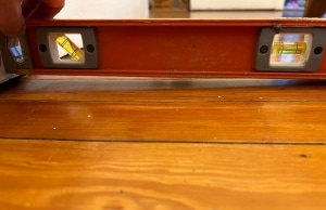 A measuring tool on the floor, showing uneven floors as one of a sign of floor sagging in Alexandria, VA.