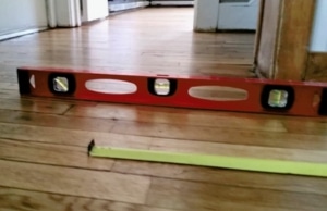 A measuring tool on the floor, illustrating uneven or sloping floors, a sign of potential sagging floors in Brambleton, VA