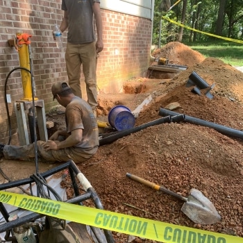 A man securing the steel bracket to the foundation footing for push piers installation in Stephens City, VA.