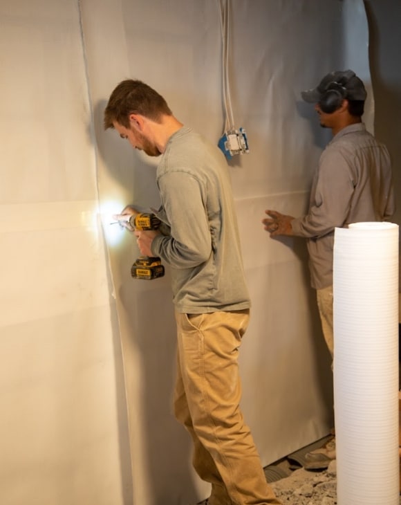 Image of LUX team installing basement wall vapor barrier in Reston, VA, for moisture control and improved energy efficiency.