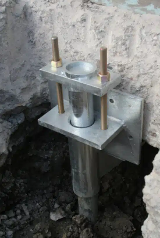 Close-up image of push piers installed beneath a building’s foundation in Front Royal, VA, for structural support.