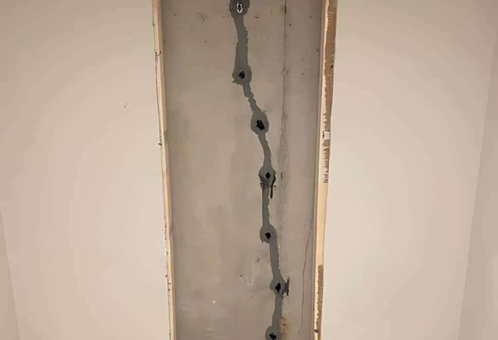 Close-up of epoxy injection being used to seal a crack in a basement foundation wall.