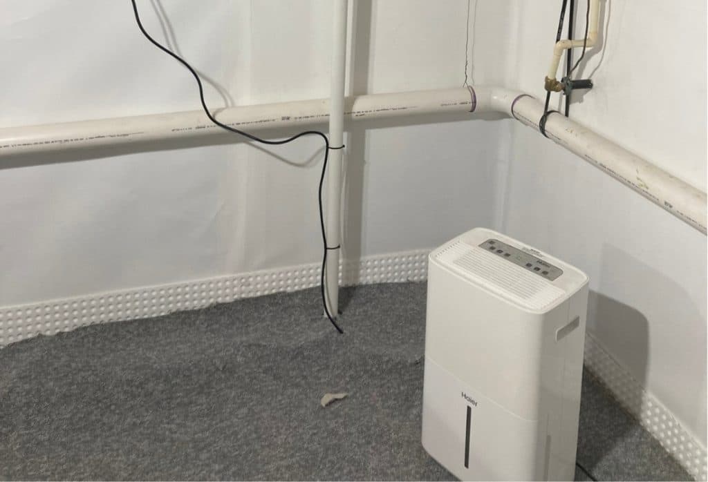 A dehumidifier running in a basement to control humidity levels and prevent mold growth.
