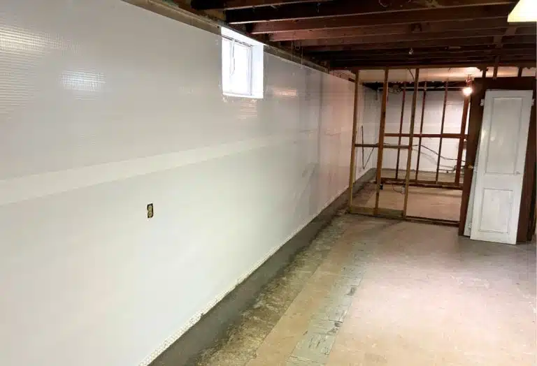 Installed vapor barrier on a basement wall to prevent moisture seepage and control humidity.