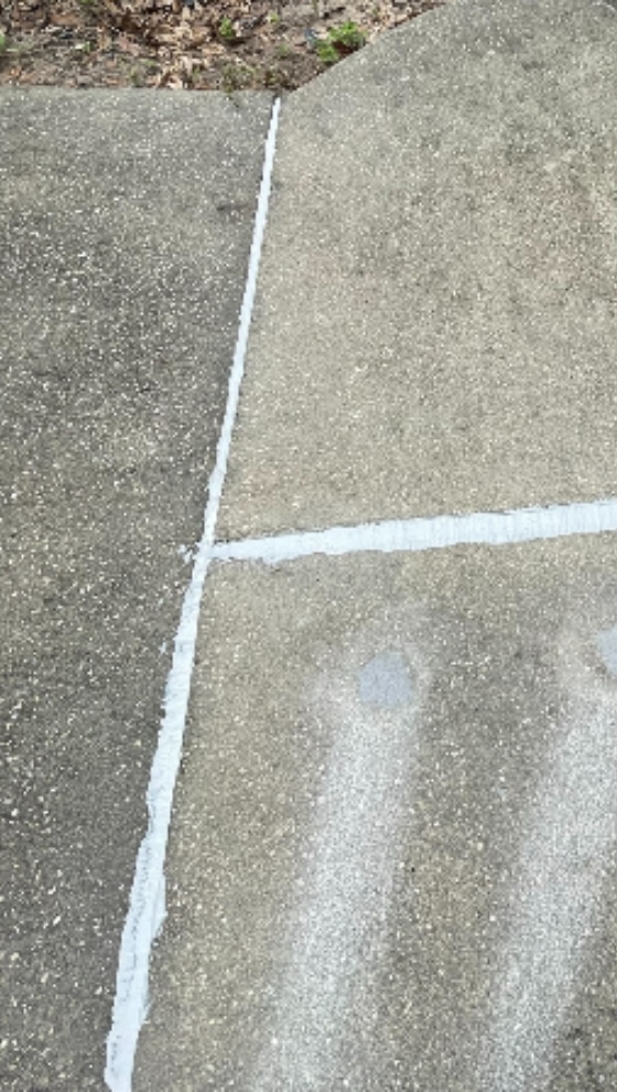 Close-up of finished concrete caulking repair in a large crack in a concrete patio.