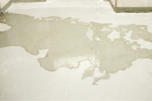 Water seeping through cracks in the basement floor, indicating a sign of an uneven basement slab in Southbridge, VA