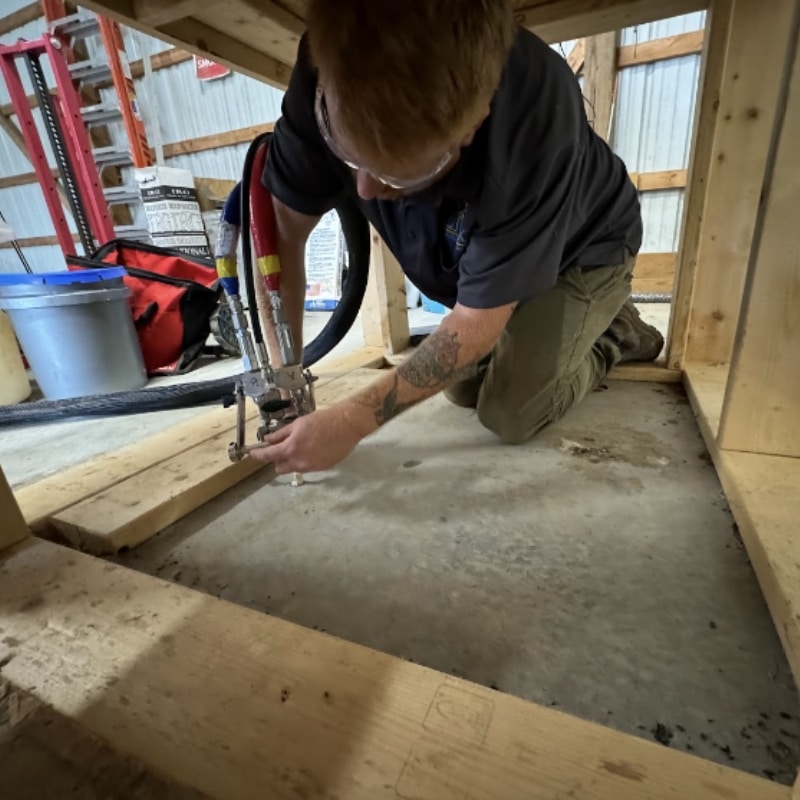 LUX team injects polyurethane foam to lift an uneven basement slab in Berryville, VA, providing a concrete lifting solution.