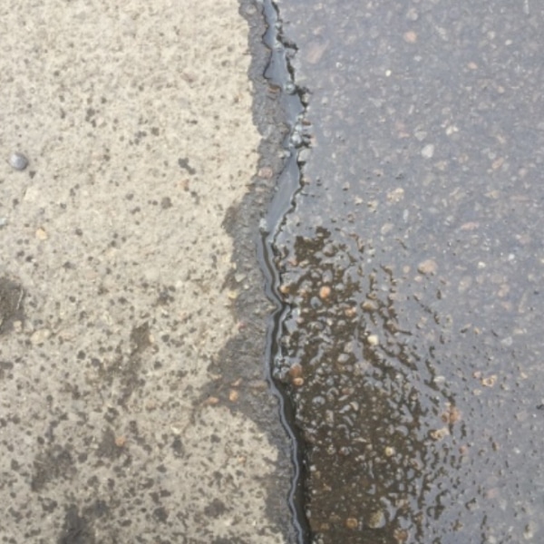 Concrete surface with moisture seeping through cracks, showing freeze-thaw cycles can cause uneven sidewalks in Warrenton, VA.