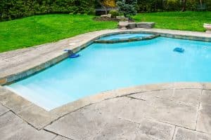 Cracked concrete pool deck with visible gaps surfaces, a sign of a sunken pool deck in Alexandria, VA, that needs concrete repair.