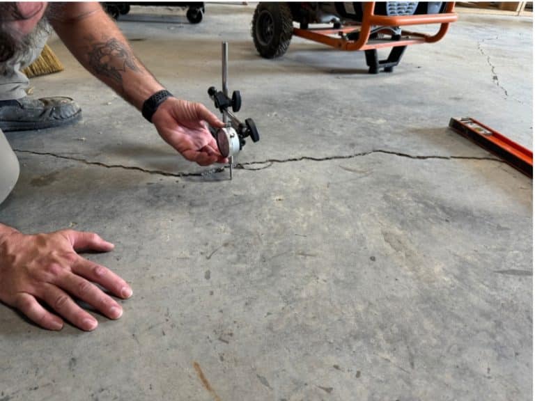 Dial indicator measuring slab movement during polyurethane foam injection for accurate concrete lifting in Stephens City, VA.