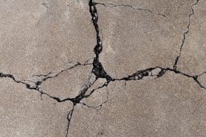 Multiple large, expanding cracks and uneven surfaces on a sidewalk, a sign of uneven sidewalks and walkways in Brambleton, VA.