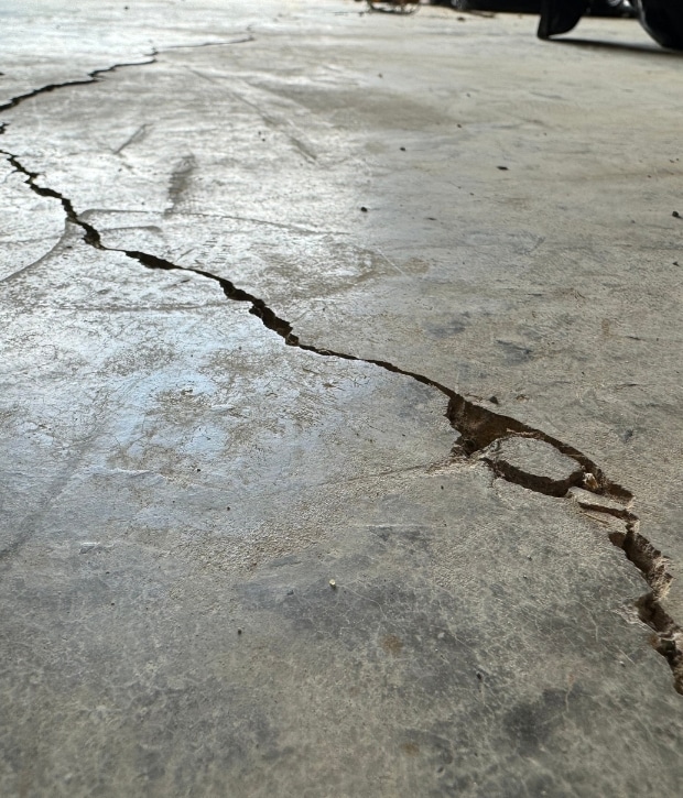 A cracked garage floor with visible concrete damage, that needs professional garage floor crack repair in Northern Virginia.