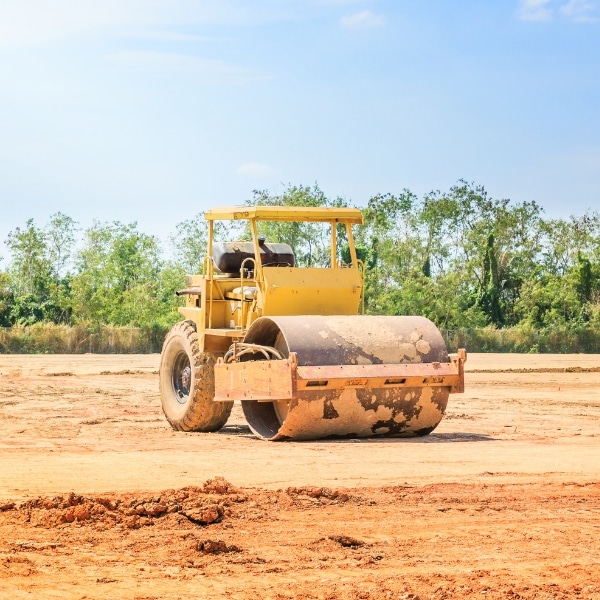 A bulldozer compacting soil, emphasizing poor soil compaction as a possible cause of a sunken pool deck in Warrenton, VA.
