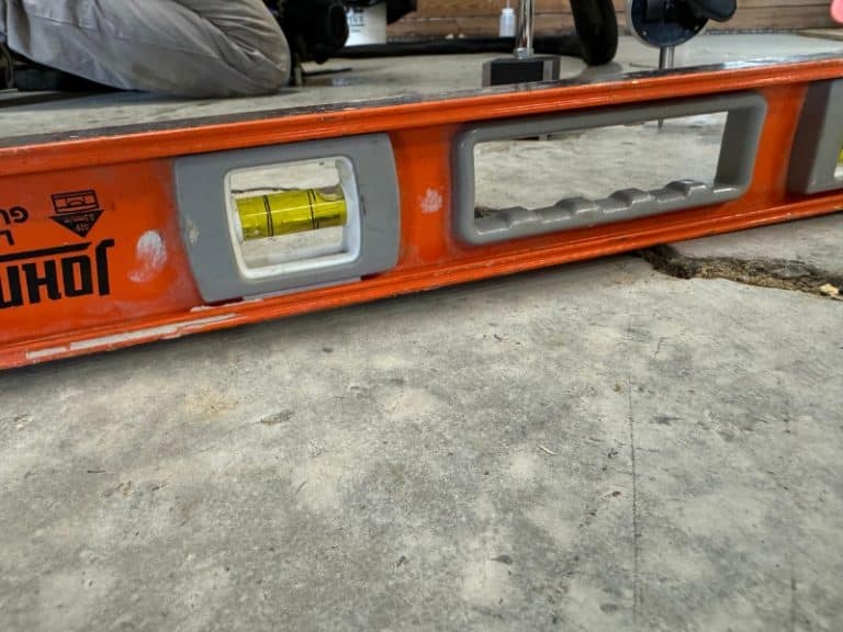 Concrete repair expert using a precision device to assess a sunken concrete slab for lifting repair in Berryville, VA.