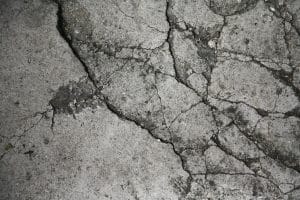 Close-up of a cracked floor with visible flaking concrete, indicating deterioration and cracked garage floor in Brambleton, VA.