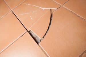 Tiled floors in the basement buckled and popped up, indicating uneven basement slab in Manassas, VA causing floor instability.