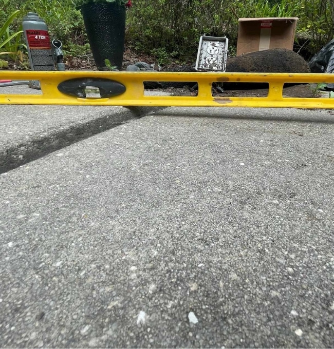 Measuring tool on a concrete sidewalk showing unevenness, indicating the need for uneven sidewalk repair in Northern Virginia.