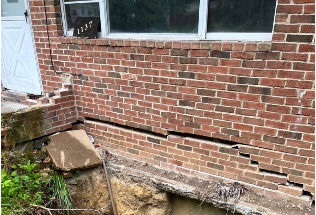 A crumbling foundation with exposed footing and settling chimney before crumbling foundation repair in  Clear Brook, VA.