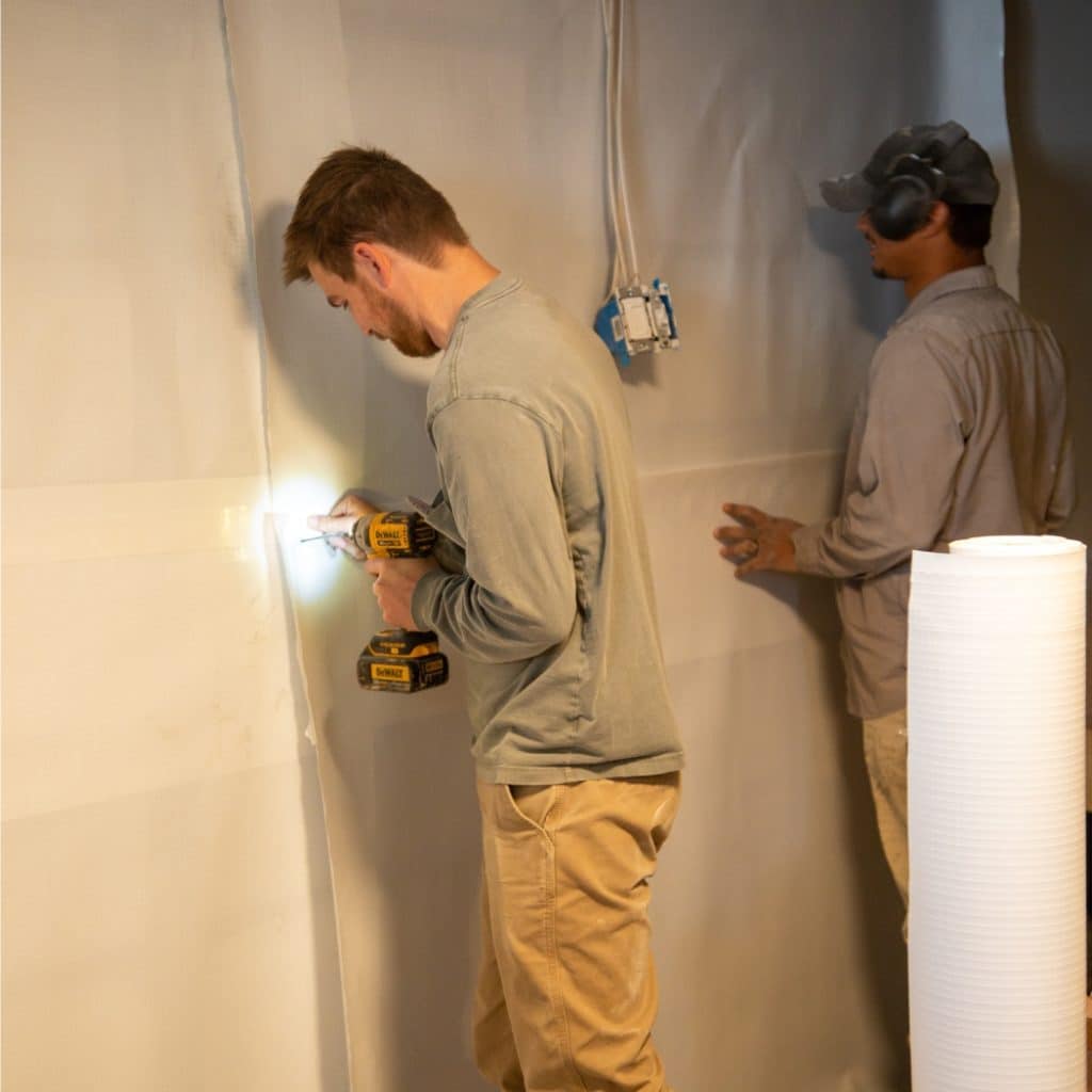 LUX team applying vapor barrier in basement walls, preventing moisture from passing through and reducing condensation in Clear Brook, VA.