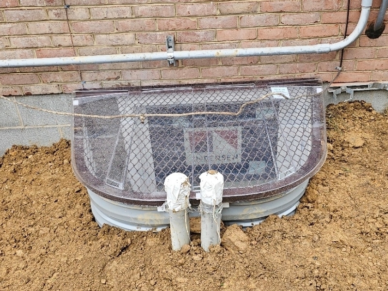 Egress window installation in Bentonville, VA, providing safe exit and integrated drainage to prevent basement water intrusion.