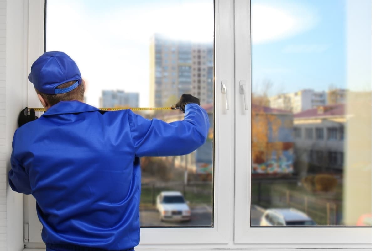 Worker fixing incorrect window installation, illustrating poor construction in Gainesville, VA as a cause of basement water damage.