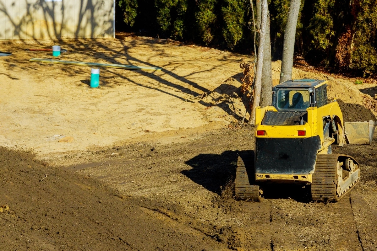 Compactor fixing poor grading around the home caused by poor construction in Marshall, VA, leading to basement water damage.