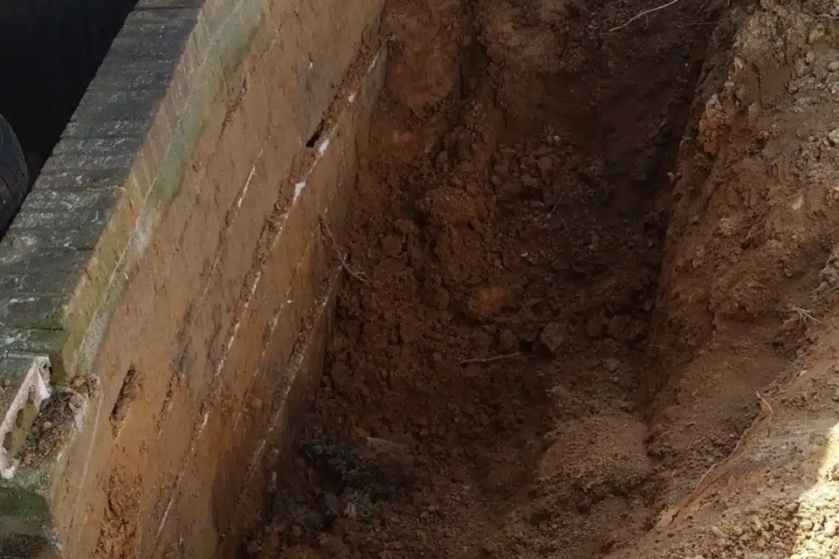 Exposed soil erosion near a foundation, showing causes of slope failure in Warrenton, VA, and potential water seepage.