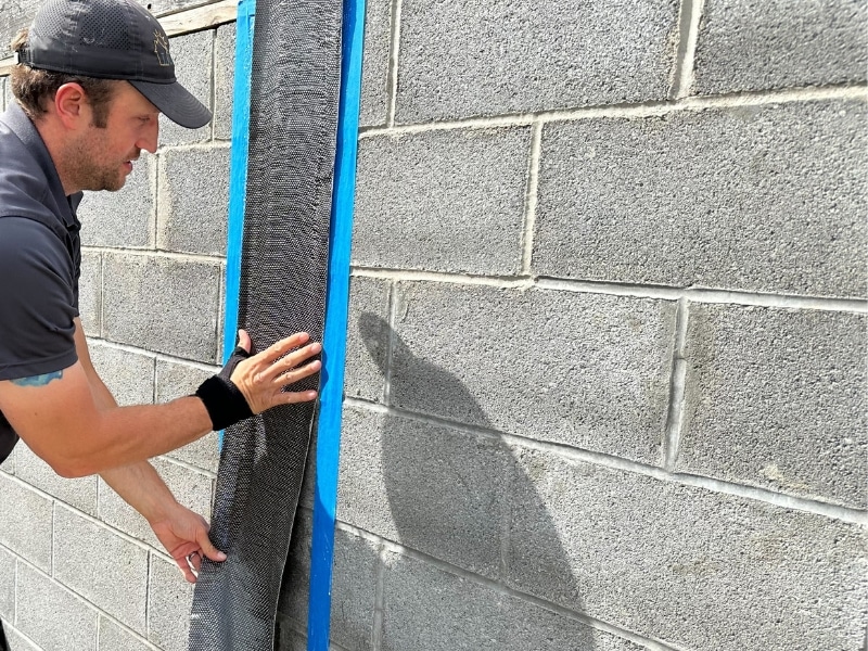 Carbon fiber strap installation on stair step foundation cracks in Berkeley WV to prevent further inward movement and shifting.
