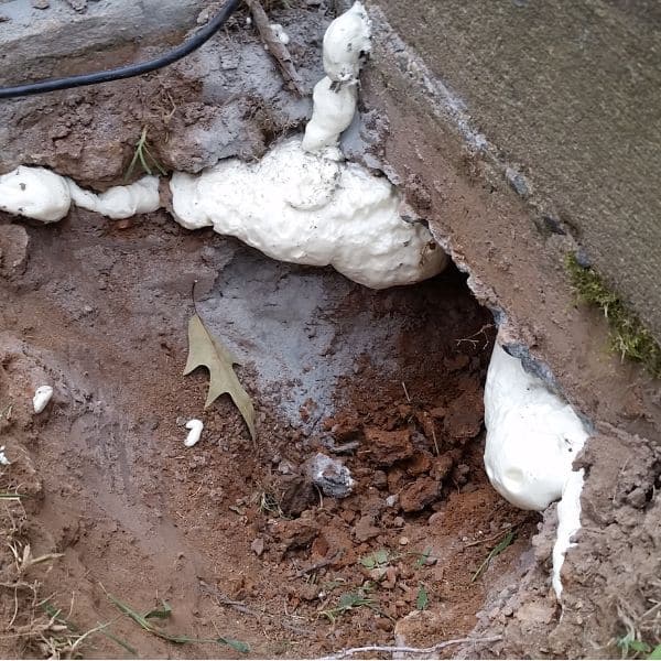 Polyurethane foam injection in concrete voids beneath foundation caused by slope movement or soil erosion in Southbridge, VA.