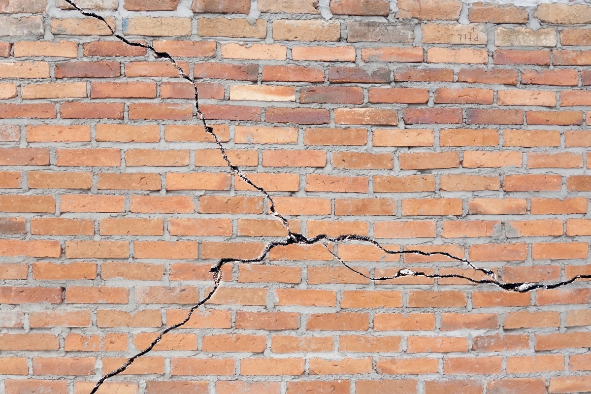 Brick foundation wall with multiple cracks caused by soil contraction during a drought, a natural disaster in Southbridge, VA.