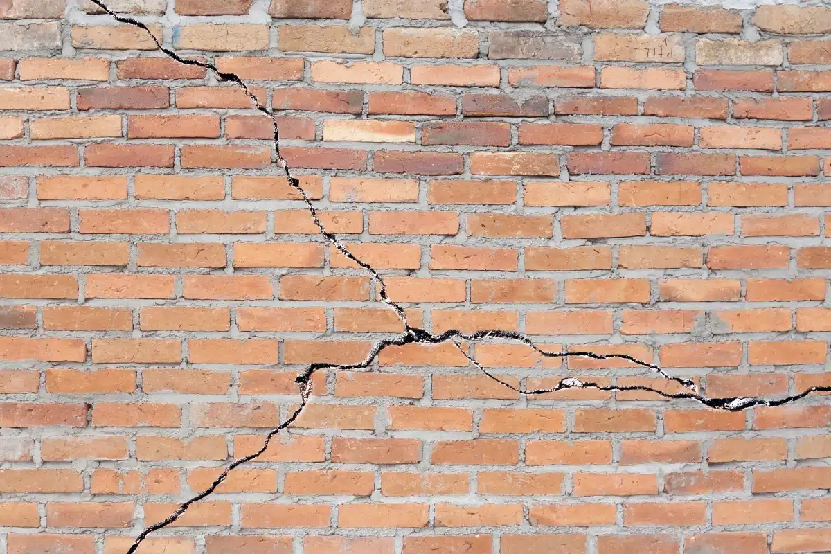 Brick foundation wall with multiple cracks caused by soil contraction during a drought, a natural disaster in Southbridge, VA.