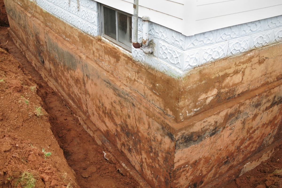 Foundation wall with excavation exposing the clay soil, showing soil type as the causes of poor soil compaction in Ashburn, VA.