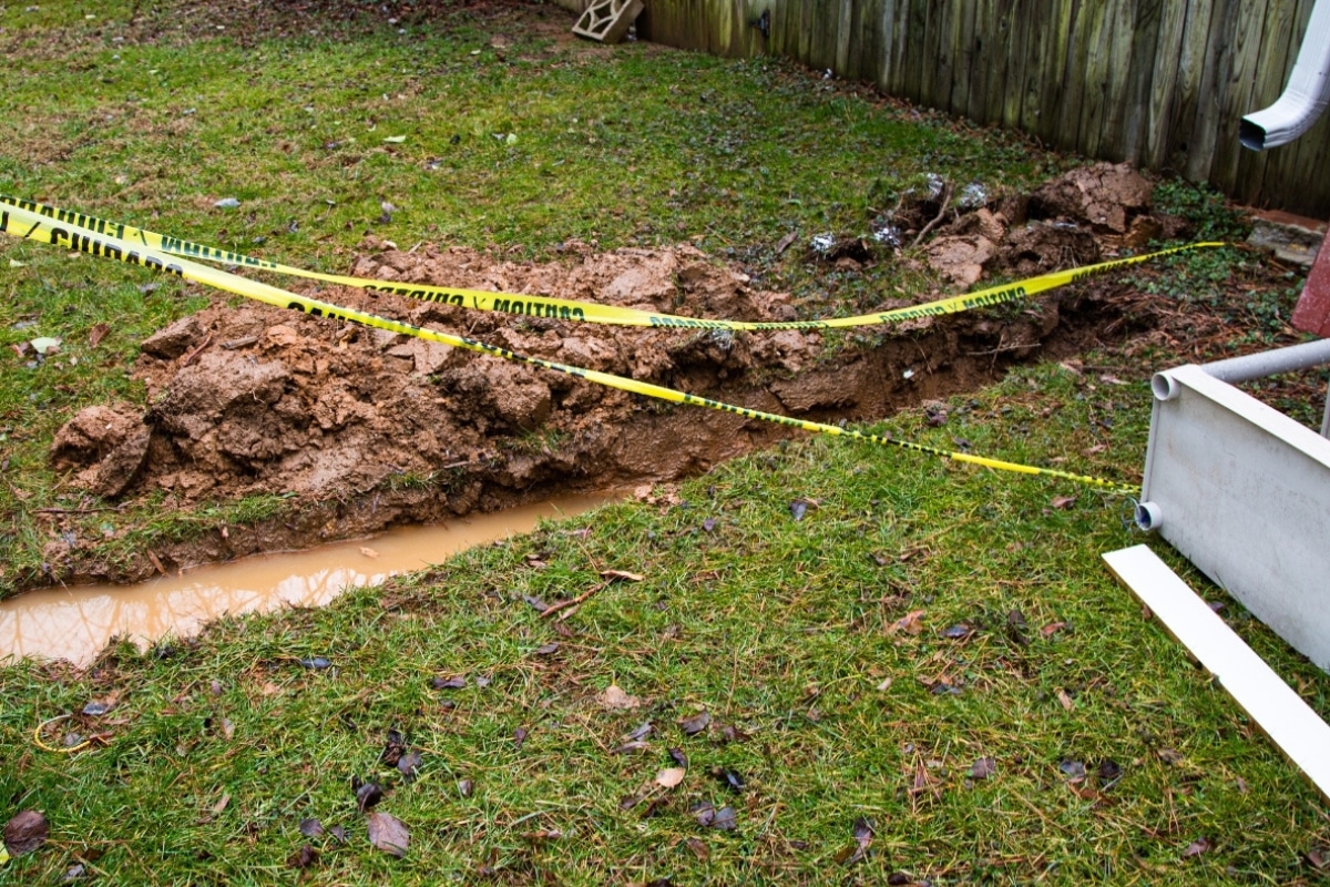 Area around a foundation with water pooling due to insufficient drainage systems in Gainesville, VA, leading to soil saturation.