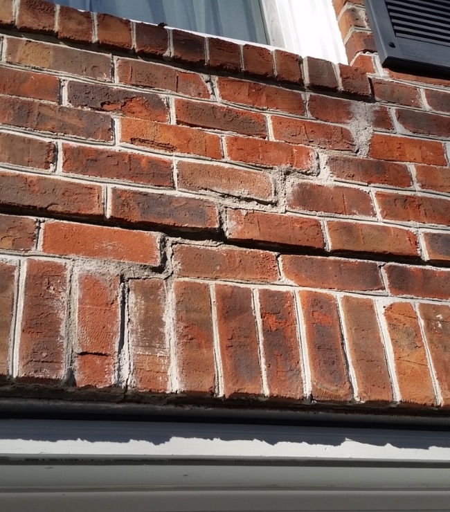 A house’s foundation brick wall with cracks affected by a natural disaster that needs foundation repair in Alexandria, VA.