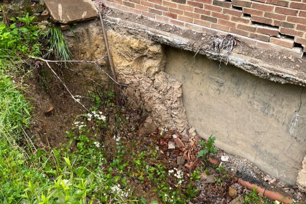 Settled ground near a foundation worsening improper soil grading in Gainesville, VA that causes crawl space moisture issues.